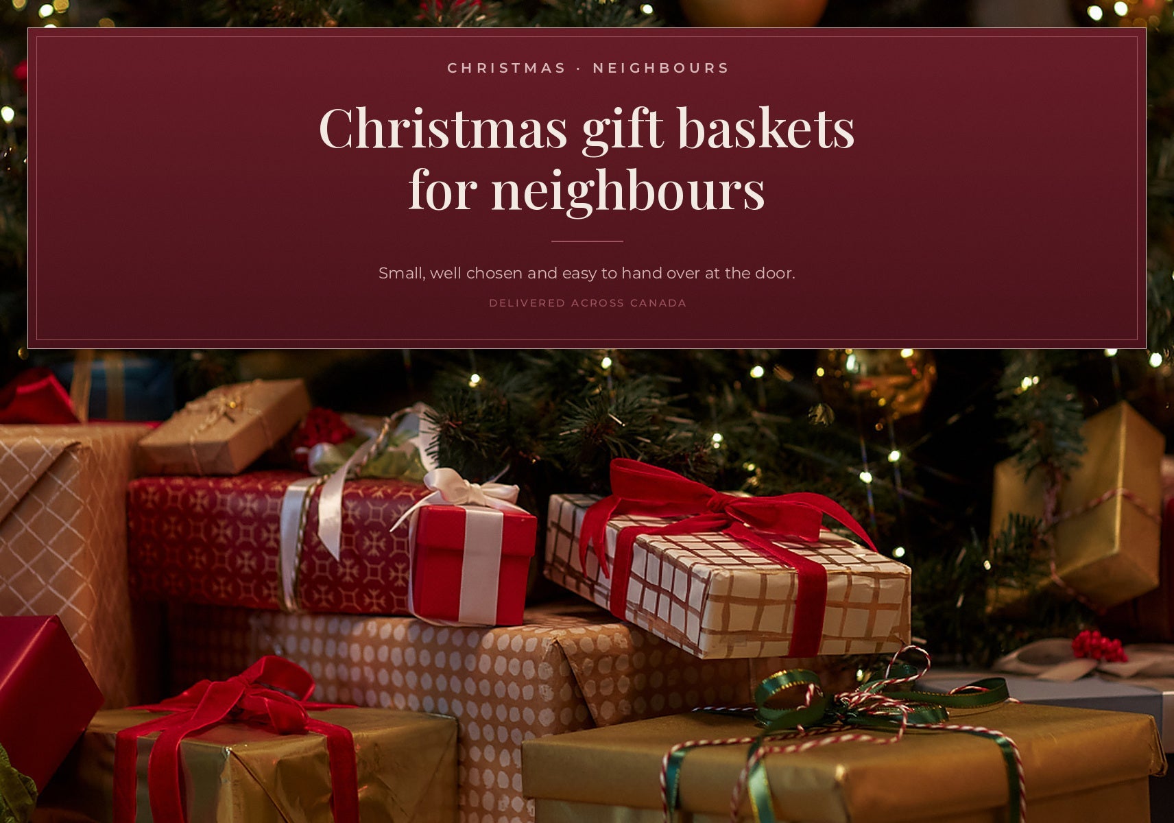 A stack of Christmas gifts with red and white patterned paper and large red bows sitting beneath a blurred Christmas tree.