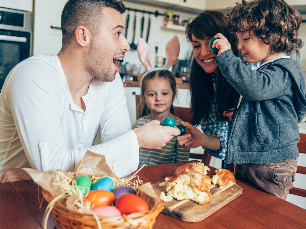 A family gathered around a table with a basket of colorful eggs and sweet bread.