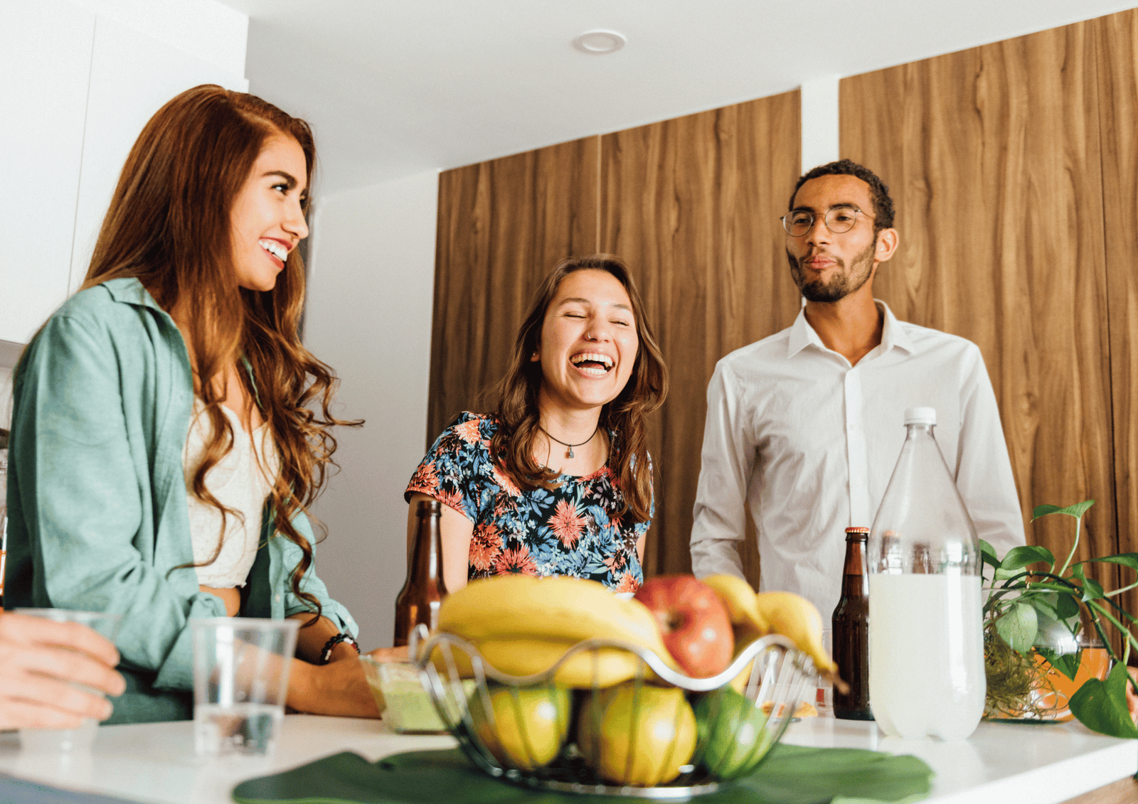 Friends laughing at a housewarming party with fruit and drinks, illustrating meaningful gifting etiquette.