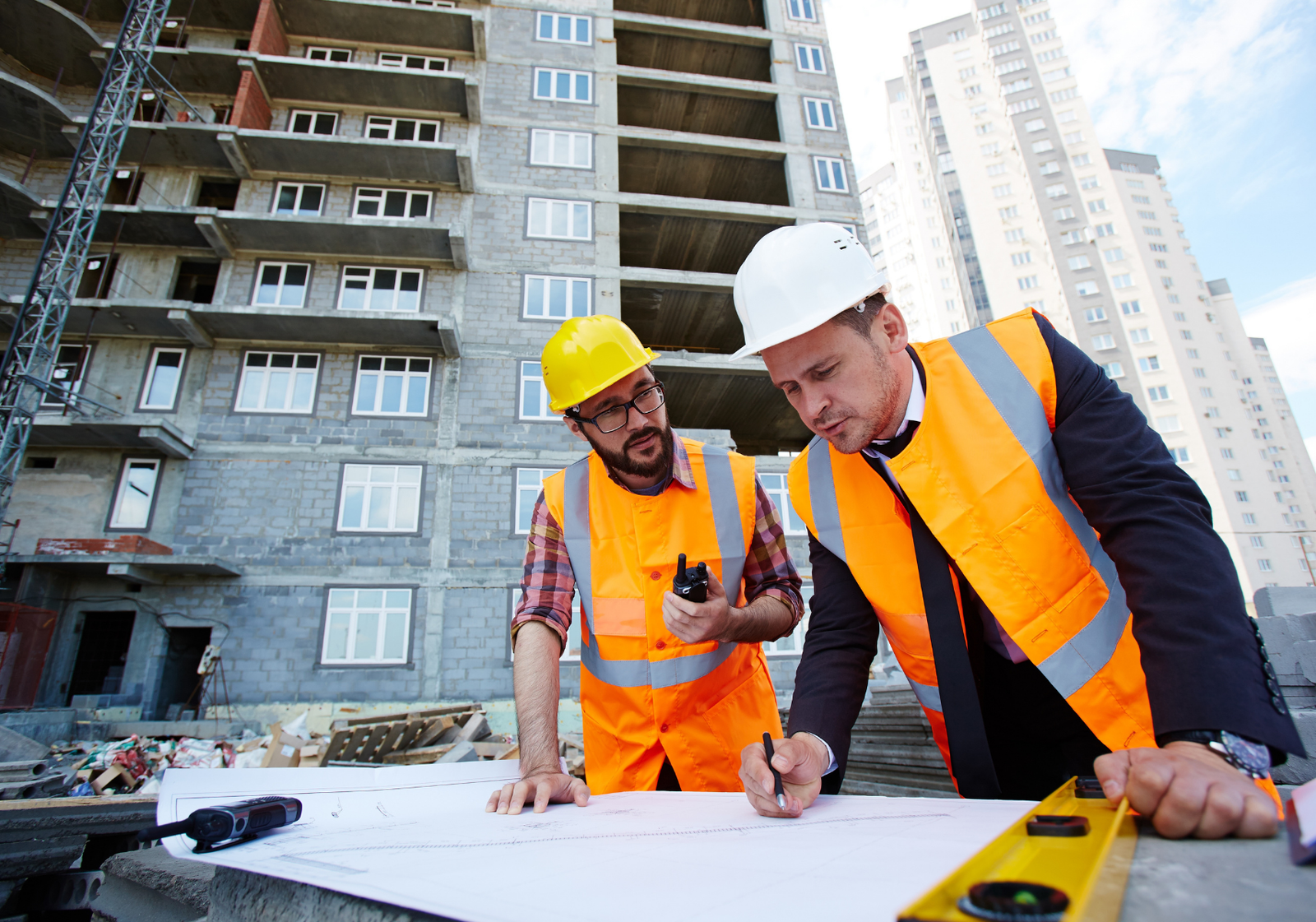 Two construction workers on-site reviewing plans, honoring hardworking employees this Labour Day.