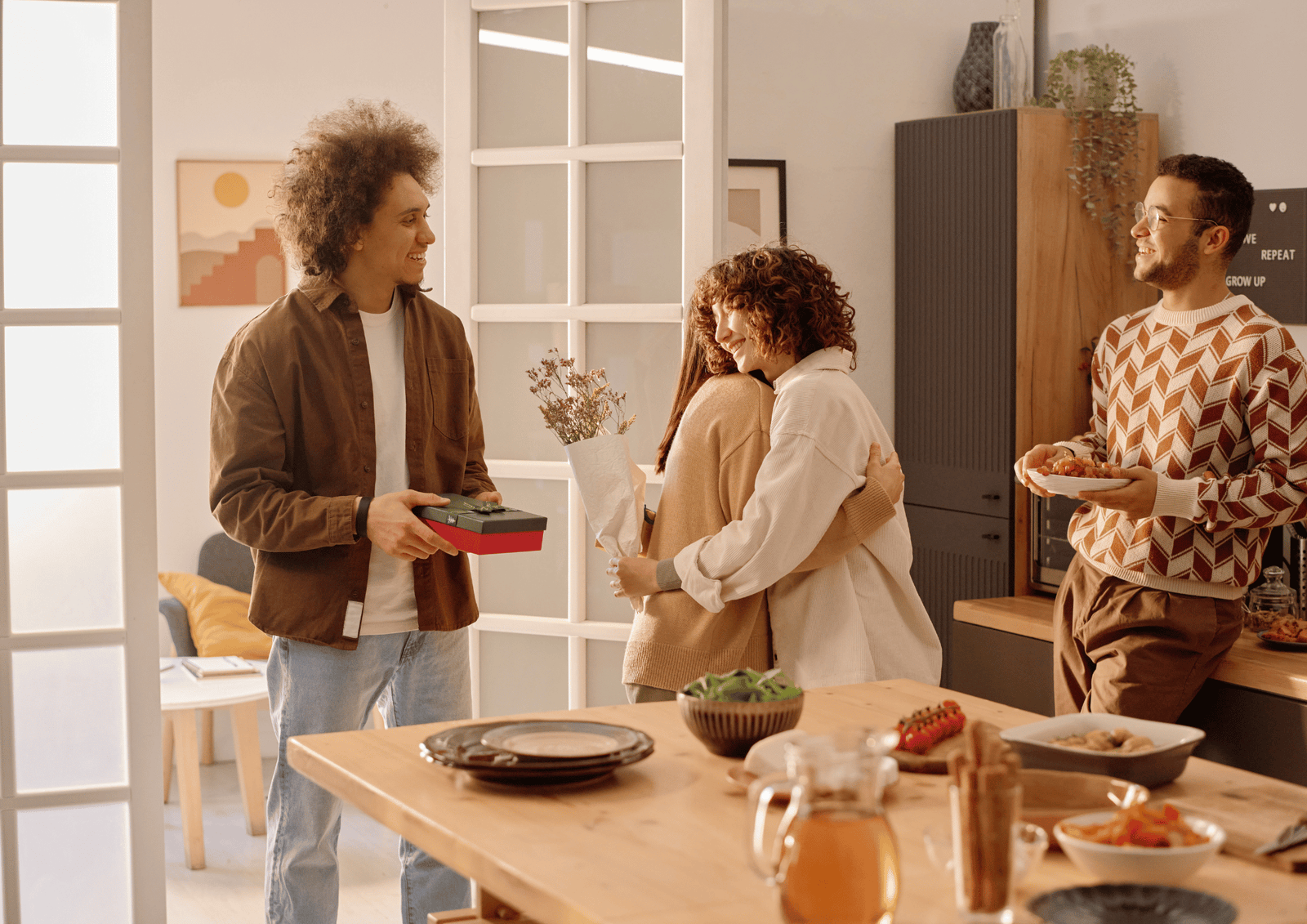 Friends celebrating a housewarming party with gifts and flowers in a modern kitchen, highlighting meaningful gifting.