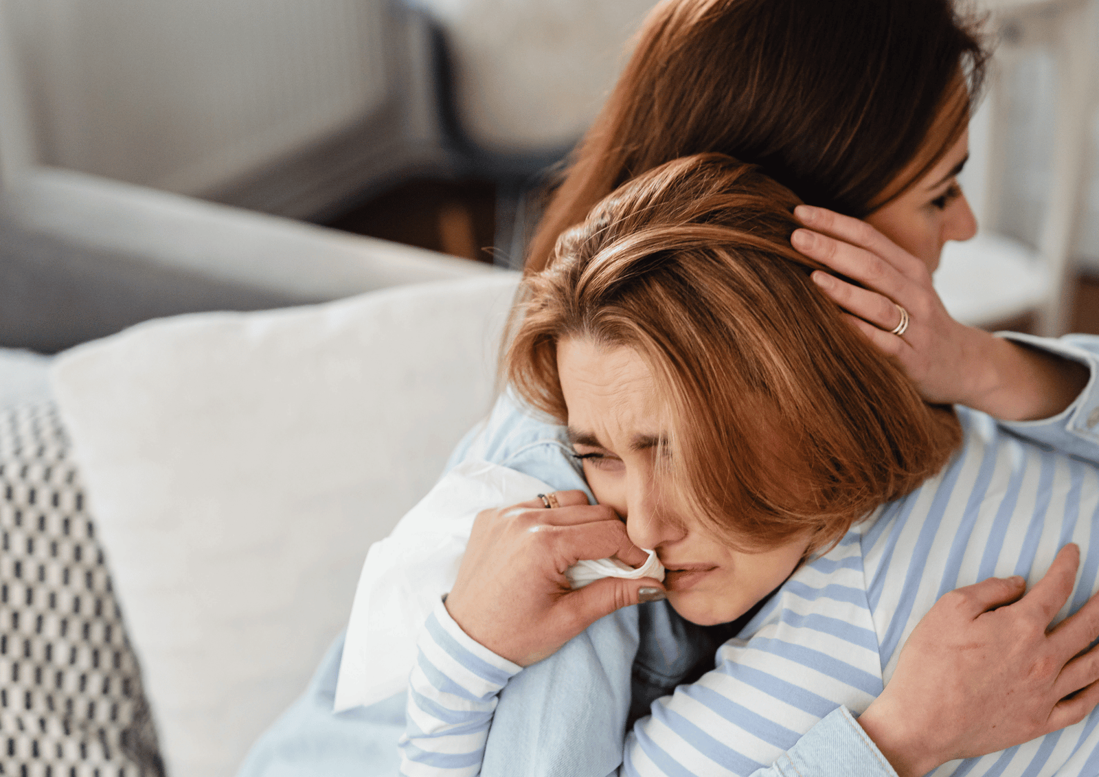 Woman comforting a crying friend with a warm embrace, representing Canadian sympathy and condolence support.