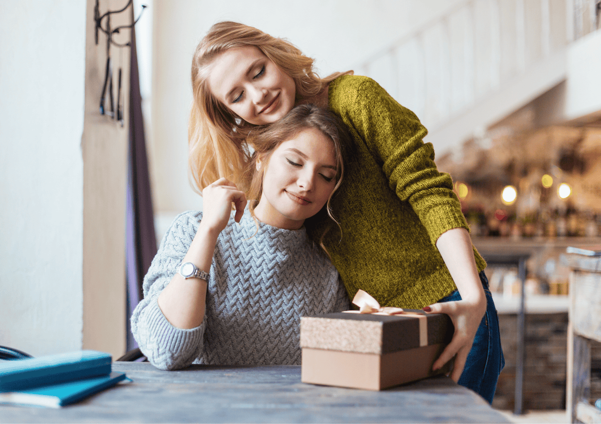 Two friends hugging while one receives a premium "Thank You" gift box.