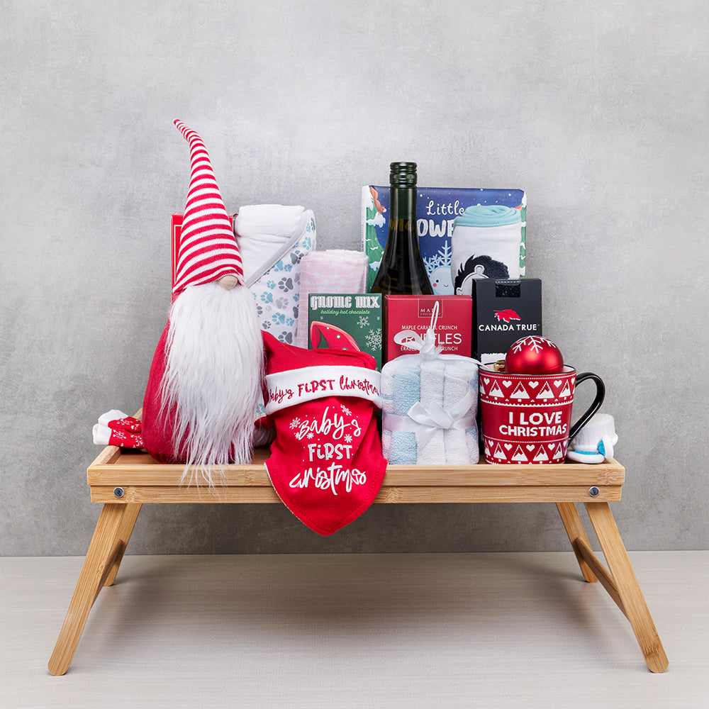 Gnome’s First Christmas Baby Gift Set: striped-hat gnome, Baby's First Christmas bib, swaddles, mug and wine on a bed tray