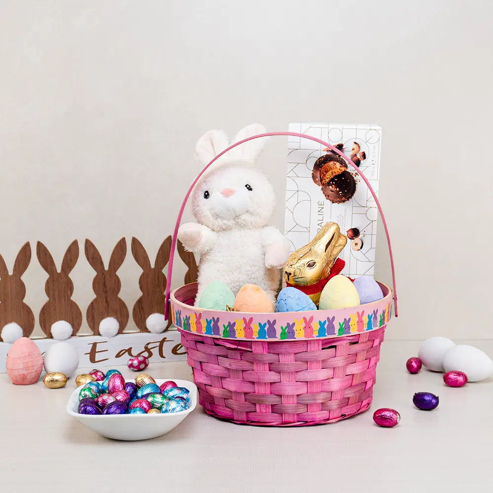 Baby Girl Easter Gift Basket in pink weave with a white plush bunny, pastel chalk eggs and a gold foil chocolate bunny