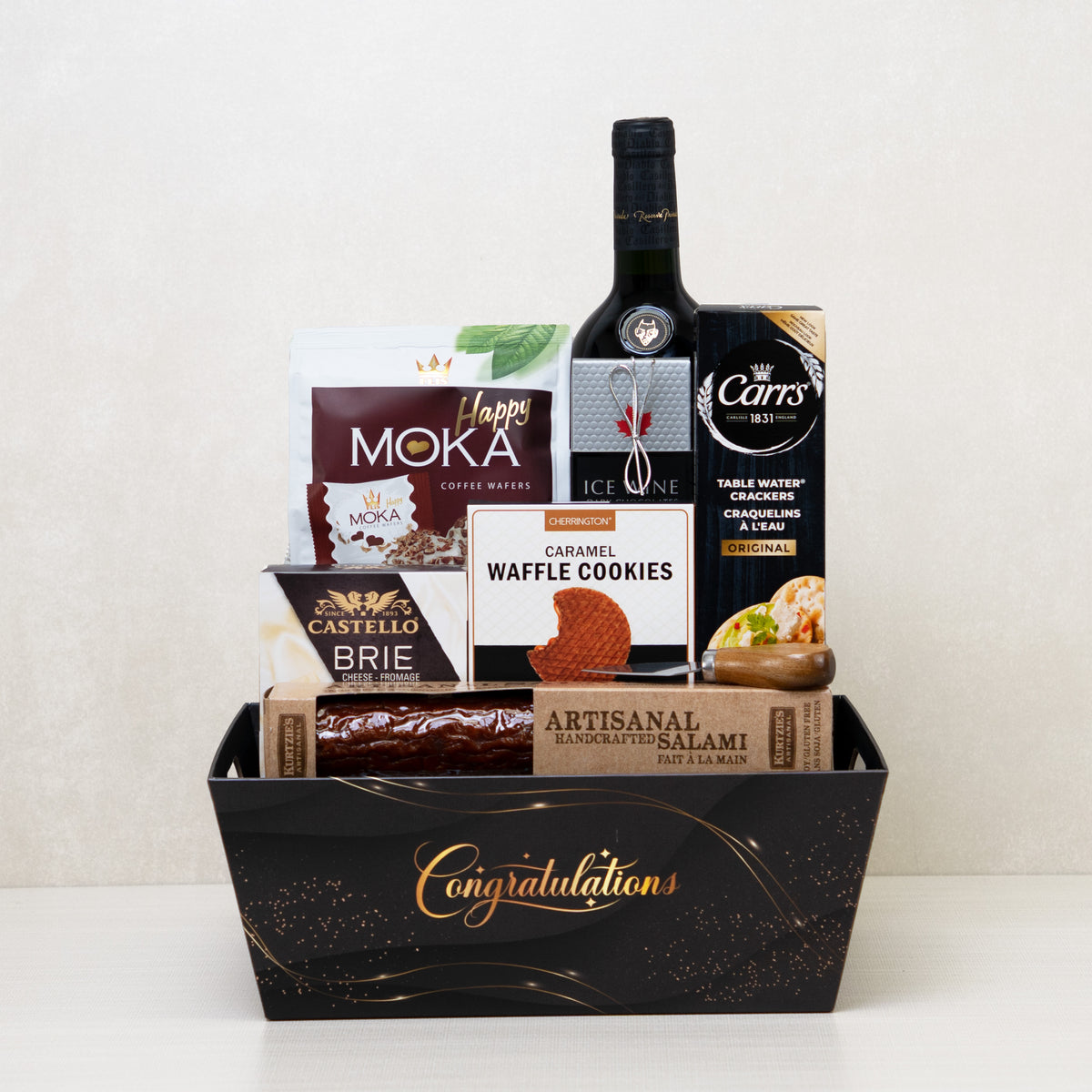 Gourmet Congratulations Gift Basket with red wine, brie cheese, artisanal salami, chocolates, crackers, and cookies.