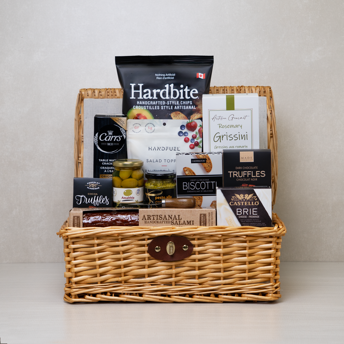 Gourmet Family Gathering Basket with crackers, chips, pesto, truffles, cheese, and more in a picnic basket.