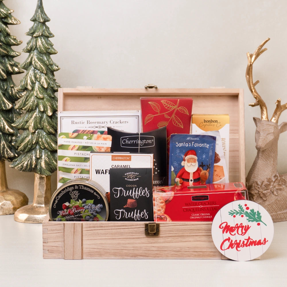 Holiday gift basket with truffles, candy drops, cocoa, cookies, crackers, and pistachios in a wooden box.