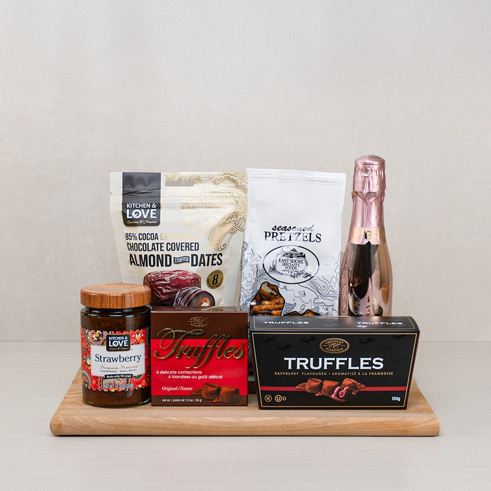 Blush & Bites Delight gift set with mini rosé bubbly, chocolate almond-stuffed dates, pretzels and truffles on a bamboo board
