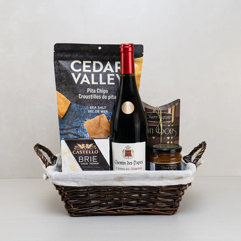 Red Wine & Savory Delights gift basket with Côtes-du-Rhône, Castello brie, pita chips and bonbons in ivory-lined wicker