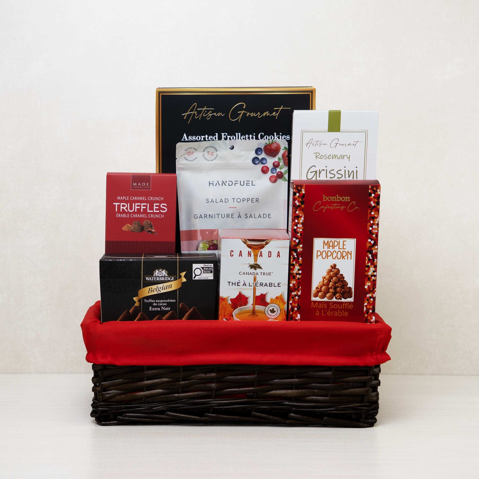 Merry and Gourmet Gift Basket: Maple popcorn, truffles, tea, breadsticks, and cookies in a willow basket.