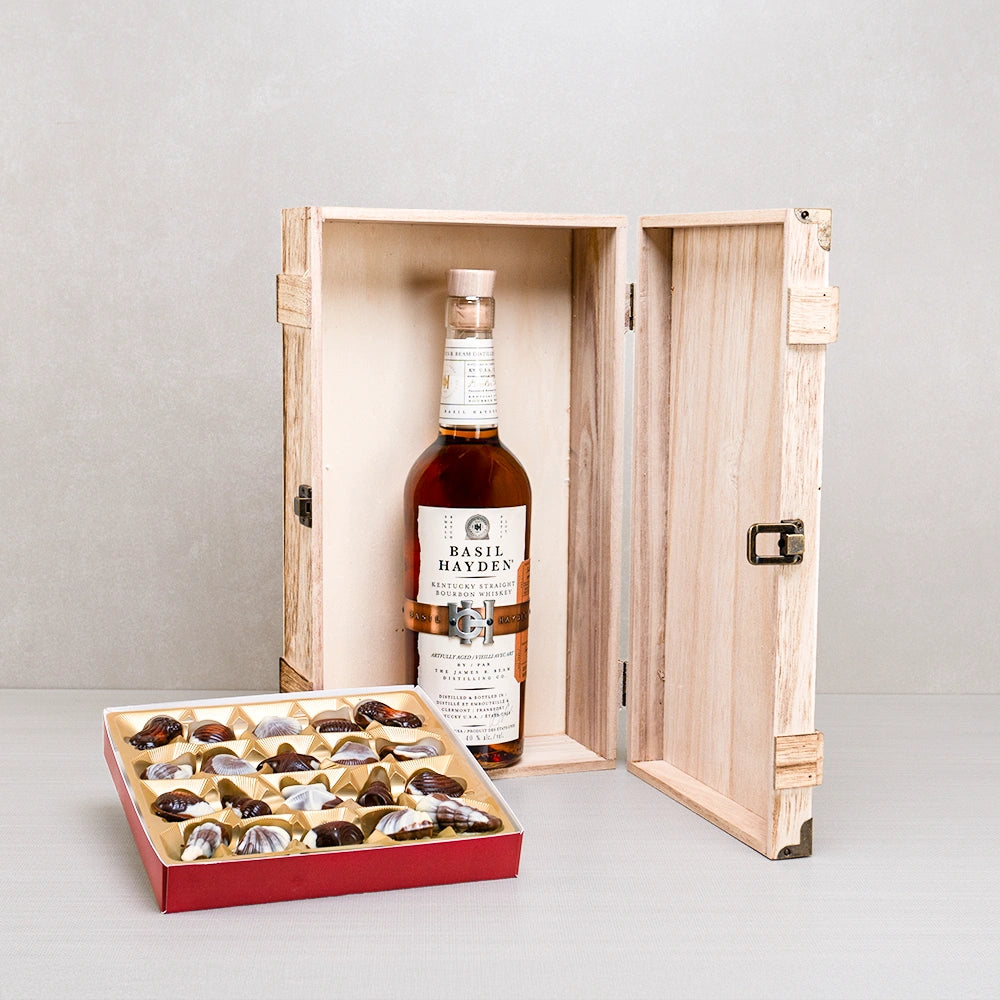 Basil Hayden’s Premium Pairing Box: Basil Hayden bourbon in a hinged wooden case beside a tray of Belgian seashell chocolates