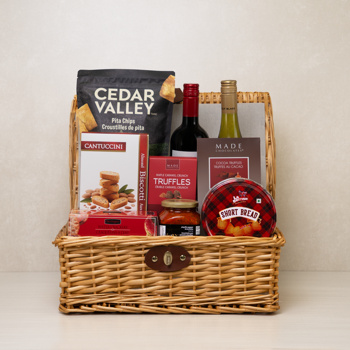 Savoury Treats Gift Basket with red wine, white wine, pita chips, truffles, and more in a picnic basket.