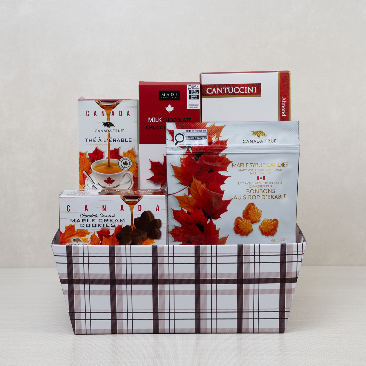 Sweet Maple Retreat Basket with almond biscotti, cookies, tea, and a milk chocolate bar in a checkered basket.