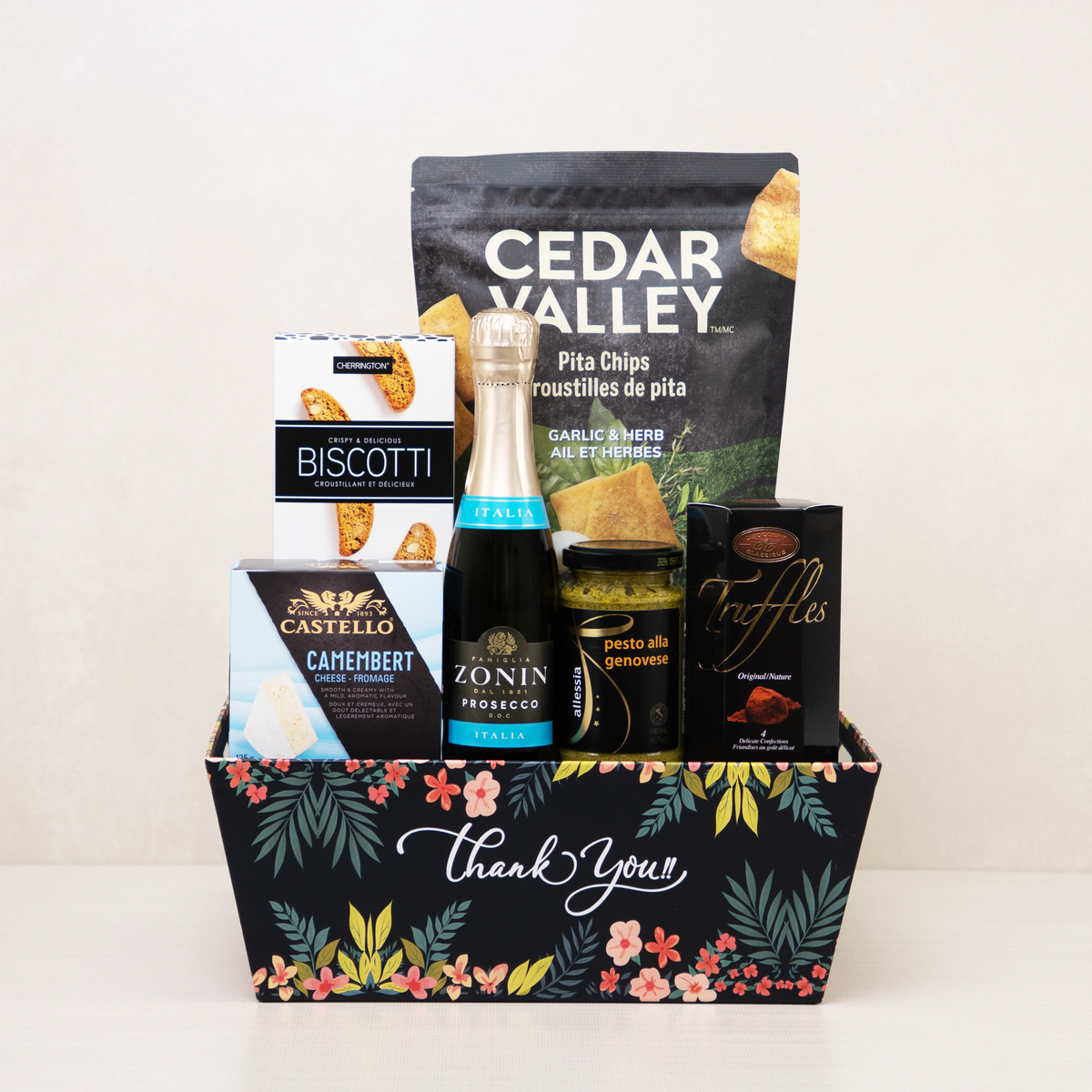 Thank You Gift Basket with mini sparkling wine, truffles, biscotti, and more snacks in a decorative floral keepsake basket.