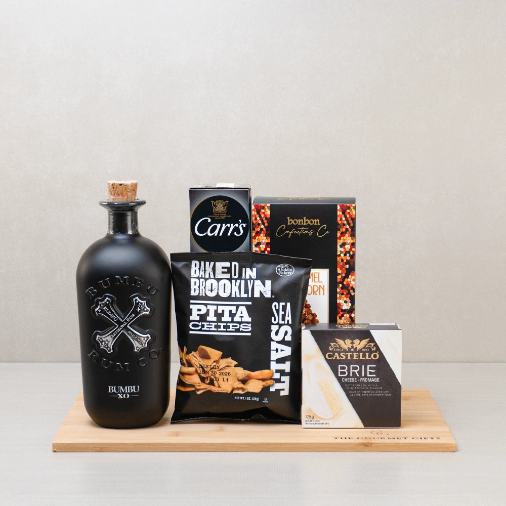 The Dark Spirit Basket with Bumbu XO rum, Castello brie, sea salt pita chips, Carr's crackers and caramel popcorn on a board