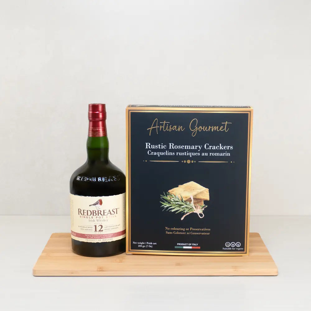 The Redbreast Treat Box with Redbreast 12 Irish whiskey and Artisan Gourmet rustic rosemary crackers on a bamboo board