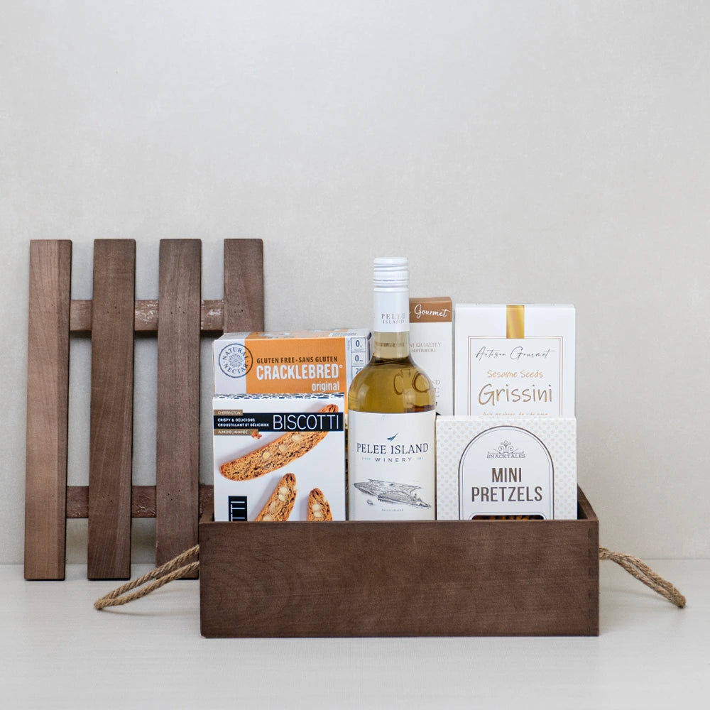 White wine gift basket with biscotti, breadsticks, mini pretzels, and coffee in a wooden crate.